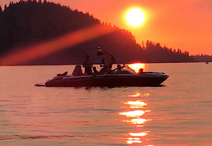 People on boat in lake at sunset